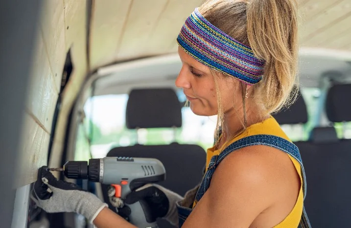 Person baut Holzwand in einem Fahrzeug